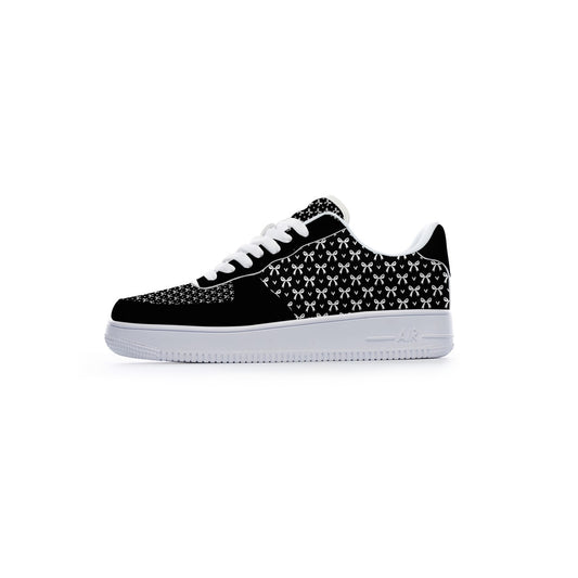 A low-top sneaker shown from the side profile against a solid white background. The shoe features a black suede toe cap, a black and white geometric patterned upper, white laces, and a thick white rubber sole.