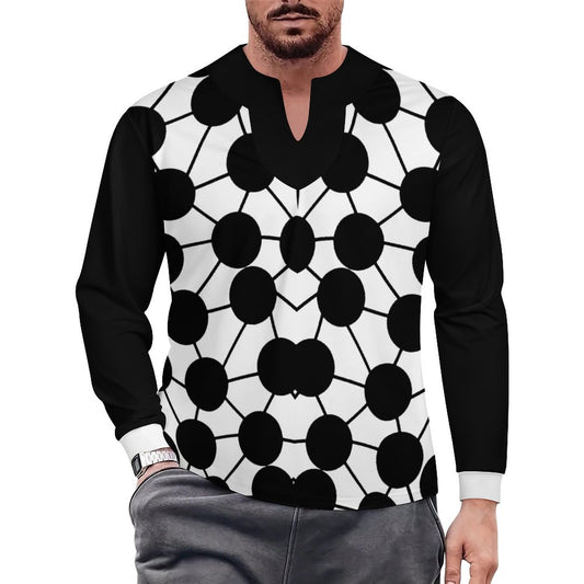 A man wearing a long-sleeve shirt with a black and white geometric pattern of large circles and lines, paired with gray pants, against a plain white background.