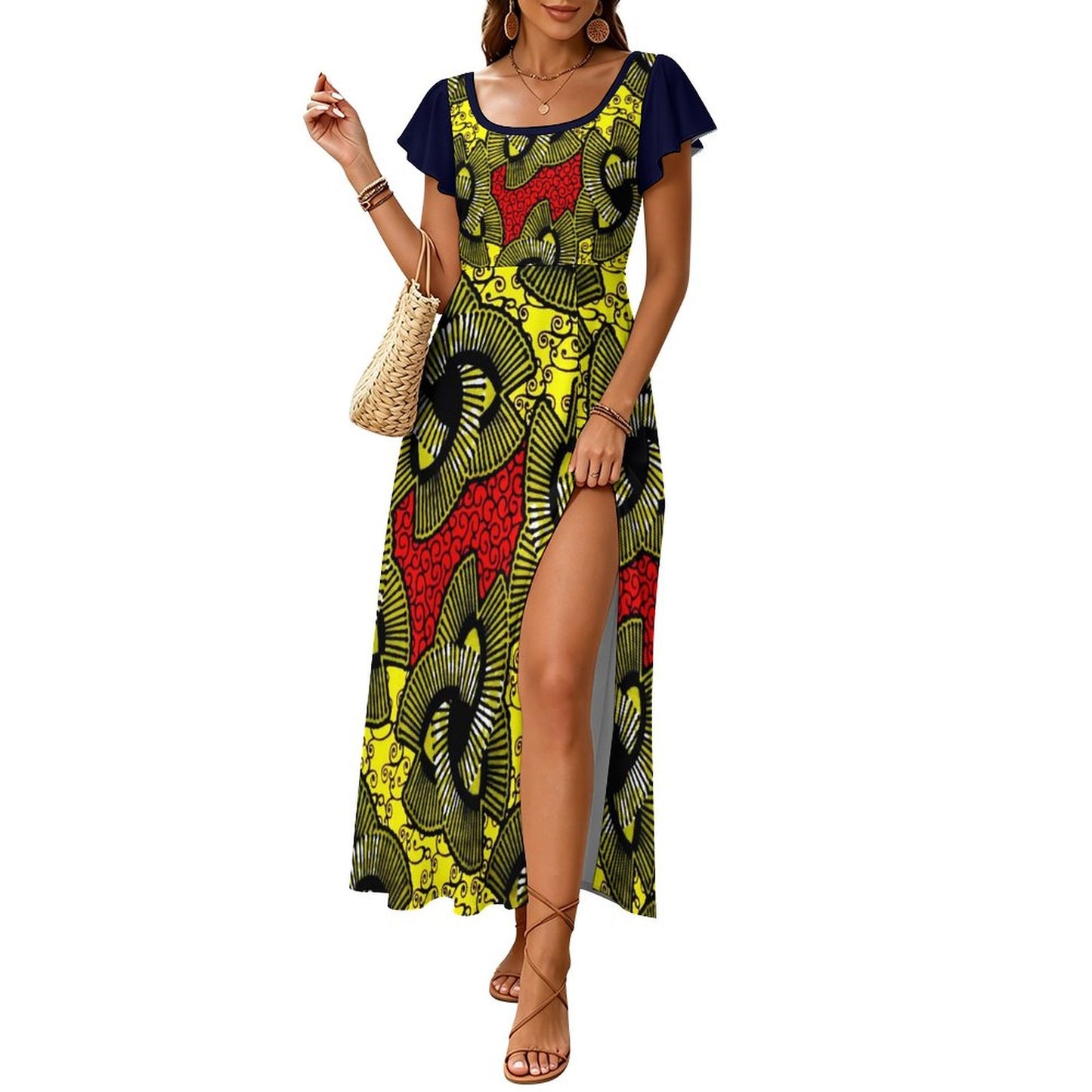A woman models a short-sleeve maxi dress with a vibrant African wax print pattern in yellow, green, red, and navy blue. The dress features a high leg slit and is styled with a woven straw handbag and brown strappy sandals against a plain white background.