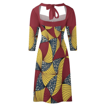 A women's midi dress with three-quarter sleeves, a scoop neckline with a tie-front keyhole detail, and a bold geometric African wax print pattern in maroon, yellow, and navy blue.