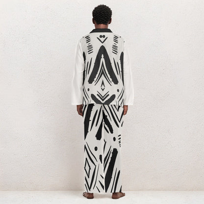 A model viewed from the back wearing a matching long-sleeve white and black geometric patterned robe and trousers set, standing against a textured off-white wall.