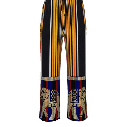 A pair of wide-leg trousers featuring a vertical striped pattern in black, yellow, orange, and white, with a decorative printed panel at the lower hem showing stylized elephant motifs.