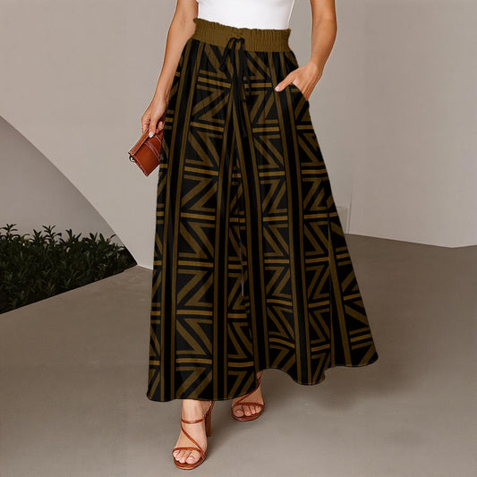 A woman models a high-waisted, wide-leg pleated maxi pant featuring a black base with a geometric olive green pattern and a matching olive green drawstring waistband. She is wearing brown strappy heels and holding a small brown leather clutch.