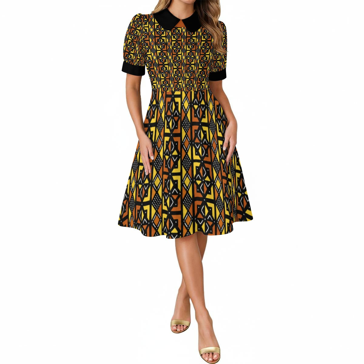 A woman modeling a short-sleeve midi dress with a black collar and a bold yellow, black, and orange geometric Kente pattern, set against a plain white background.