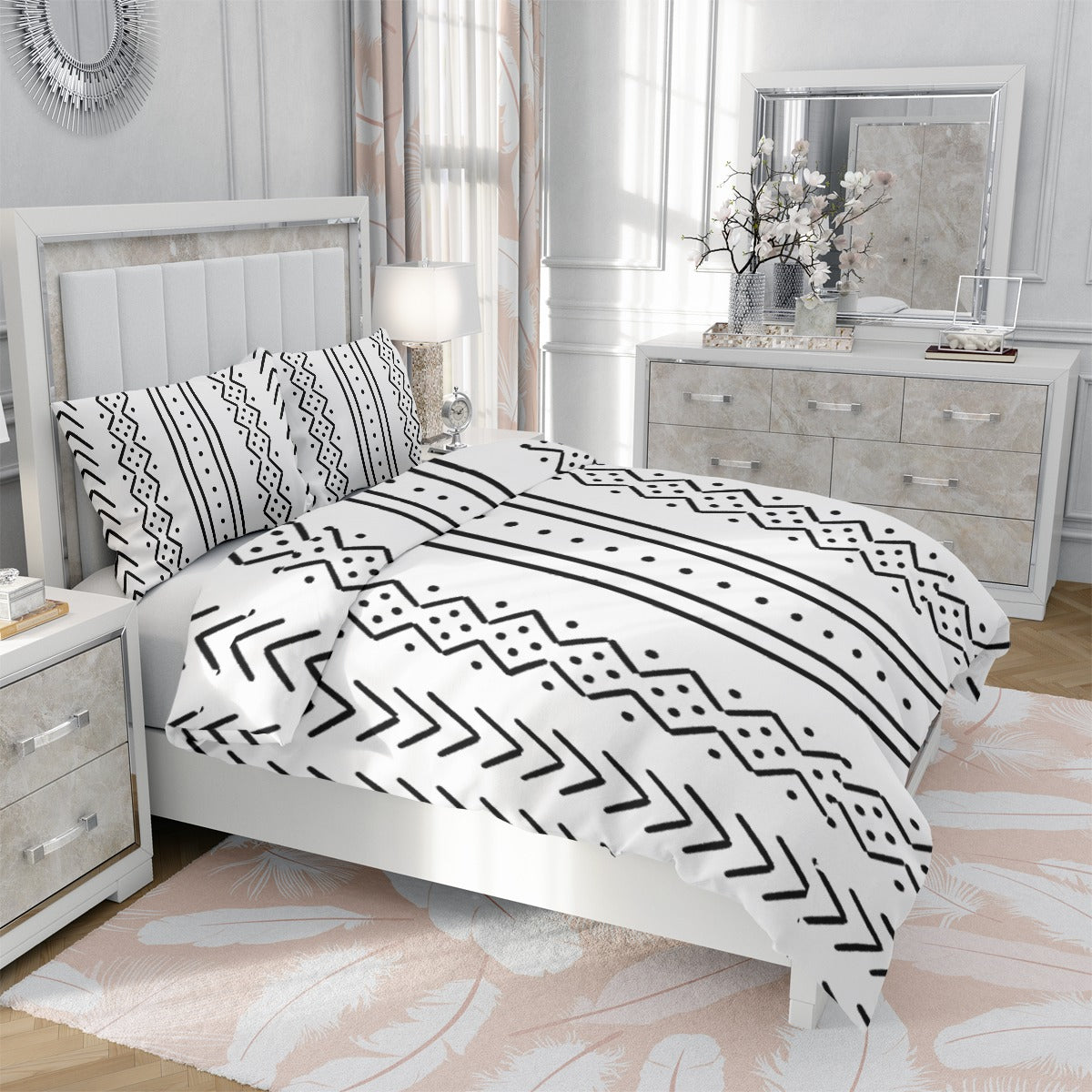 A white bedding set with a black geometric tribal pattern, styled on a white bed in a bright, modern bedroom with light pink accents.