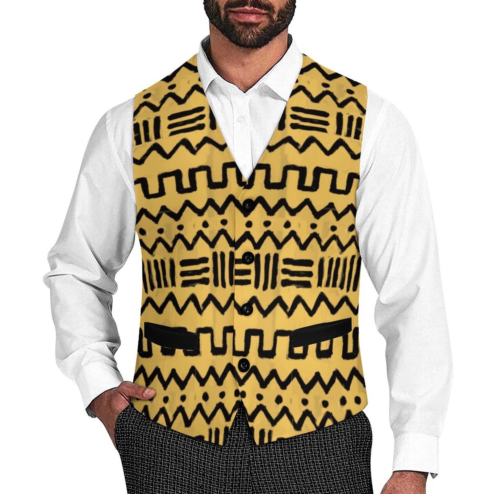 A man wearing a yellow vest with a black geometric tribal pattern over a white collared shirt and dark patterned trousers, shown from the chin down on a plain white background.