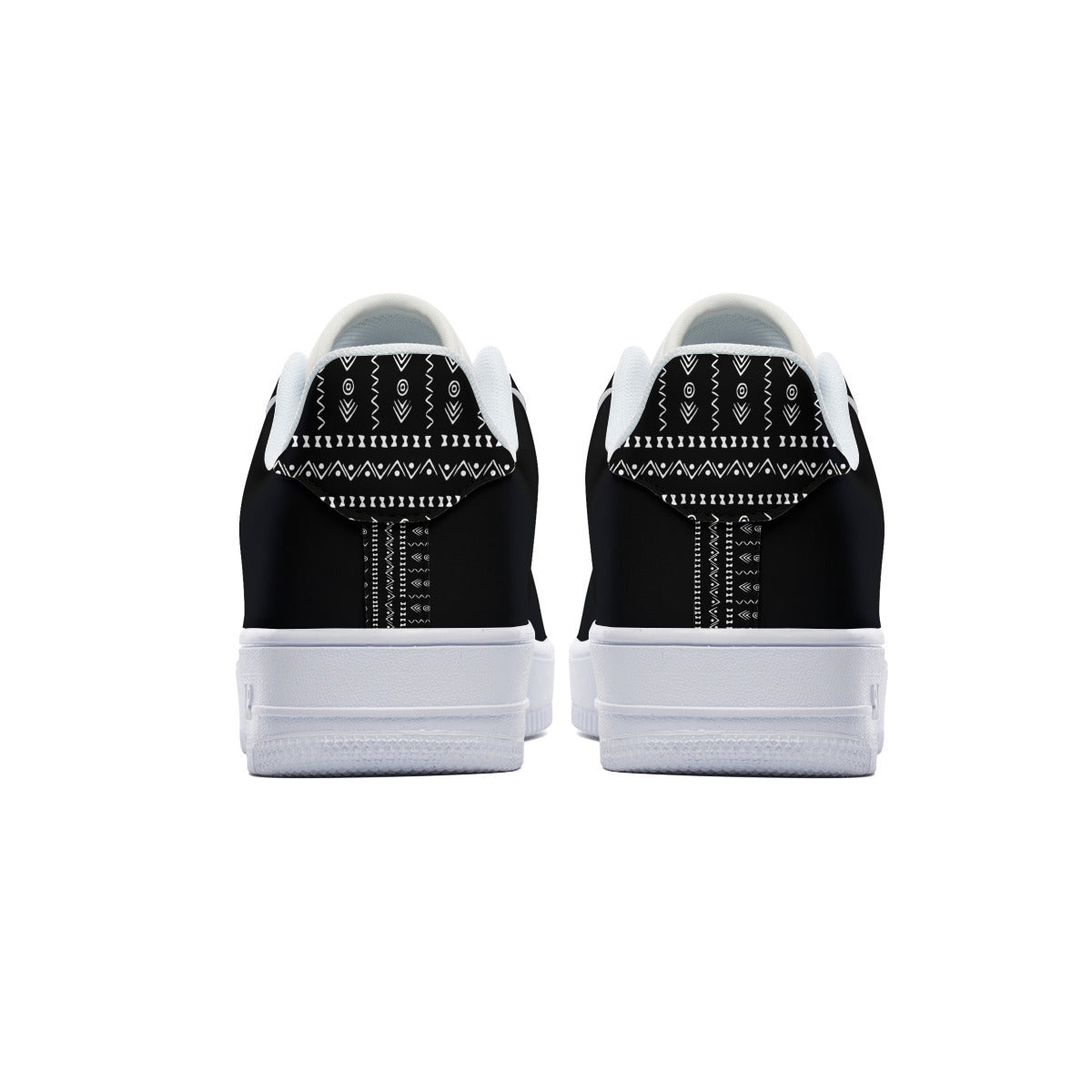 A pair of black and white low-top sneakers shown from the back, featuring a black canvas upper with white geometric patterned details and thick white rubber soles.