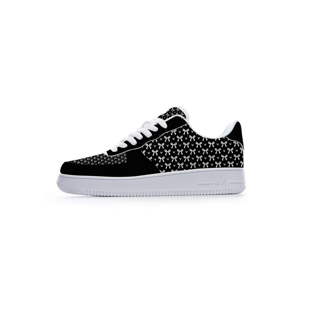A low-top sneaker shown from the side profile against a solid white background. The shoe features a black suede toe cap, a black and white geometric patterned upper, white laces, and a thick white rubber sole.