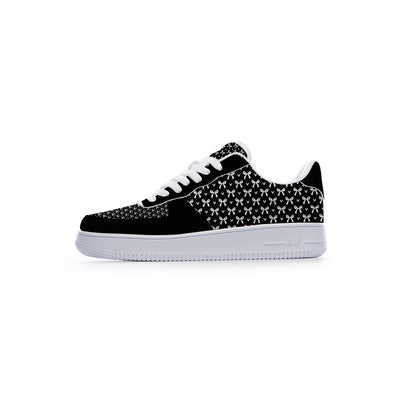 A low-top sneaker shown from the side profile against a solid white background. The shoe features a black suede toe cap, a black and white geometric patterned upper, white laces, and a thick white rubber sole.
