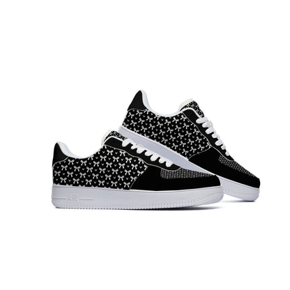 A pair of low-top sneakers in black and white, featuring a black and white geometric pattern on the side panels, white laces, and white soles, set against a plain white background.