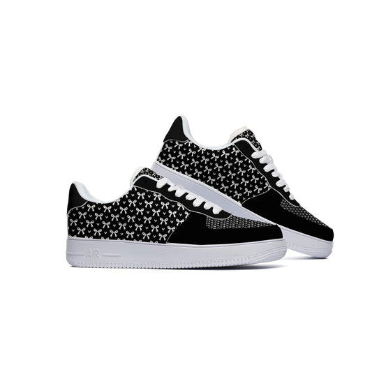 A pair of low-top sneakers in black and white, featuring a black and white geometric pattern on the side panels, white laces, and white soles, set against a plain white background.